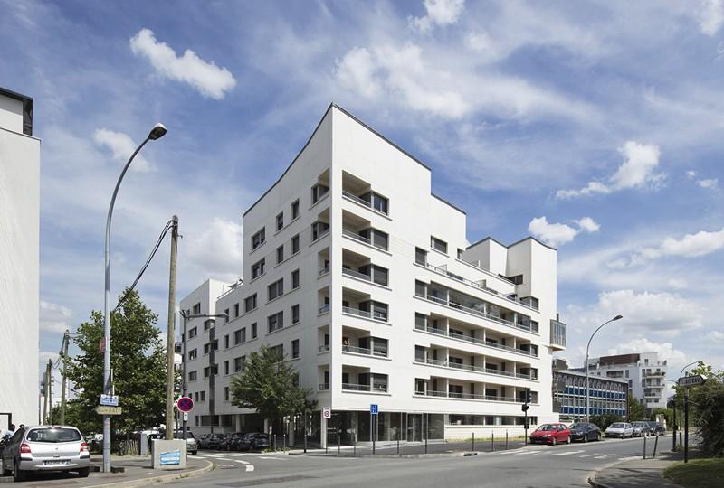 À l’angle des deux rues, où l’ouverture du hall d’accueil dessine la partie basse de l’immeuble, la pente de la toiture anime la partie haute.