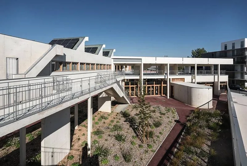 Le jardin met à distance la voie publique des salles de cours. le volume ovoïde en avant de la façade sud délimite l’entrée particulière de la salle de sport.