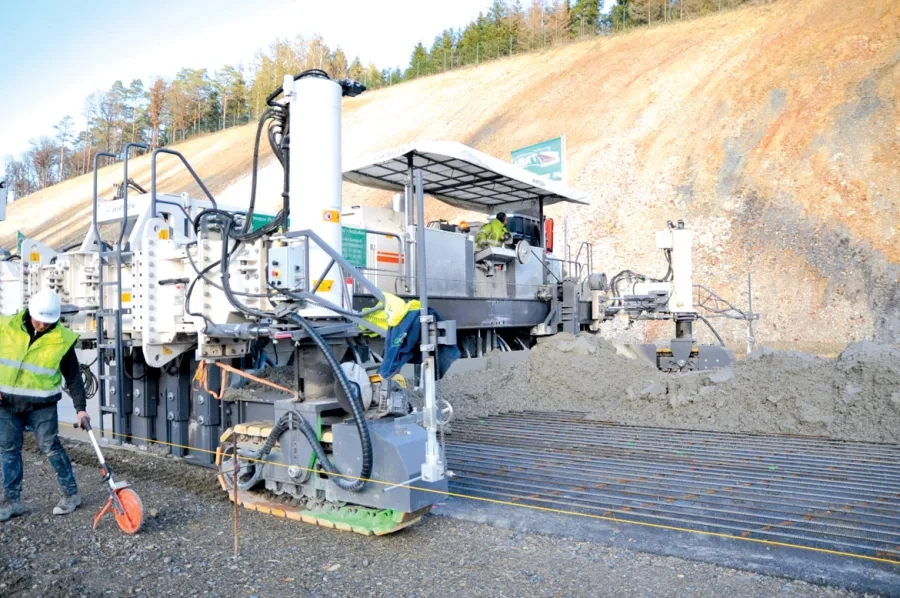 Assurant en une seule opération le coffrage et la vibration, la première machine à coffrages glissants (Wirtgen SP 1500) bétonne sur 17 cm d’épaisseur et sur 10 m de largeur. Au premier plan, le fil de guidage.