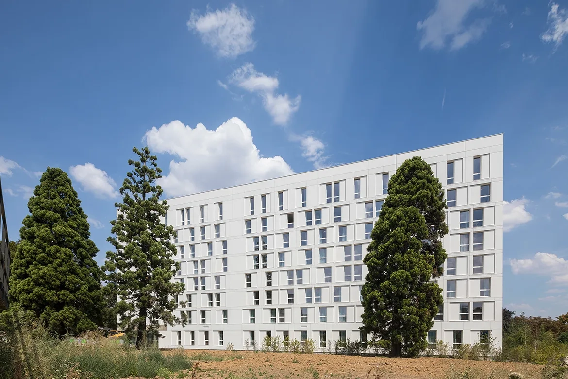 La façade ouest, plus fermée car exposée aux nuisances et composée de panneaux de béton blanc dépolluant. La façade ouest, plus fermée car exposée aux nuisances et composée de panneaux de béton blanc dépolluant.