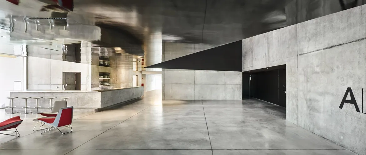 Le hall est le cœur du projet. Les surfaces de laque noire, associées à celles laissées en béton brut, animent et complexifient la perception de l’espace. Le hall est le cœur du projet. Les surfaces de laque noire, associées à celles laissées en béton brut, animent et complexifient la perception de l’espace.