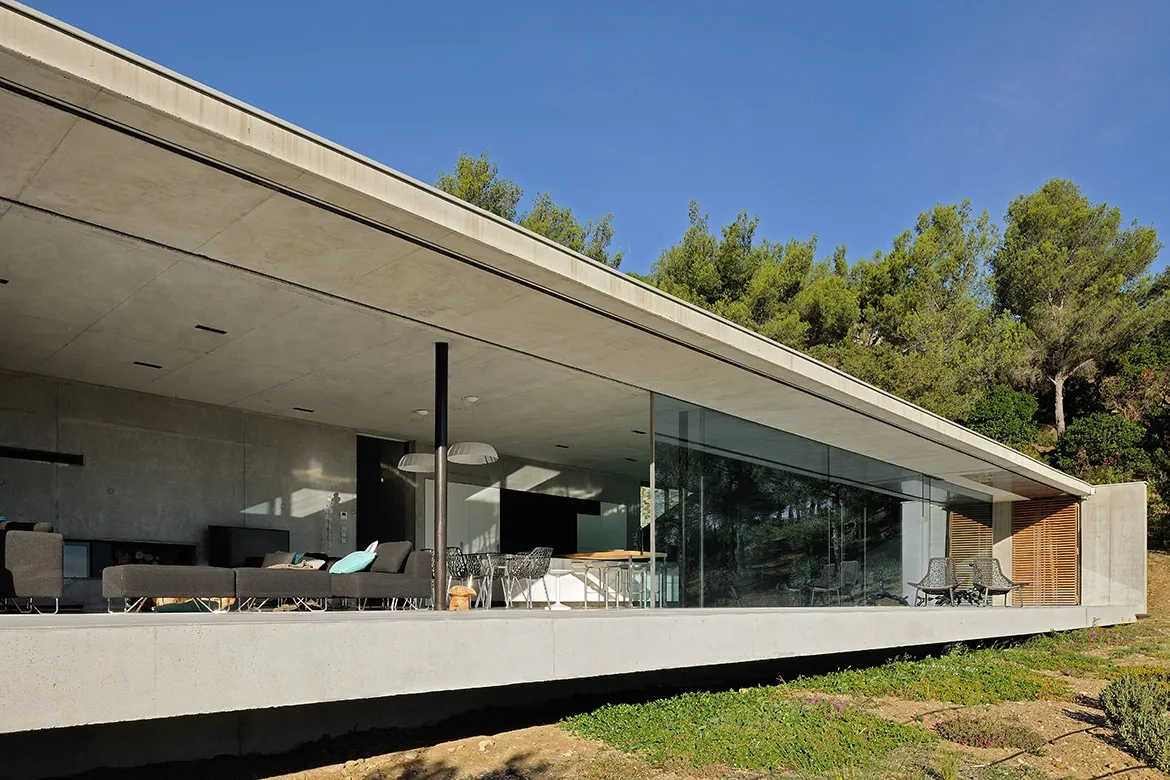 Le volume inférieur prend la forme d’un parallélépipède rectangle allongé en béton brut, dont la longue façade entièrement vitrée offre une vue panoramique sur la mer