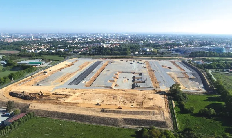 Deux vues aériennes du chantier, l’une en avril 2017 (où le traitement de plate-forme s’achève), l’autre deux mois plus tard, en juin 2017 (où la construction des premiers bâtiments commence).