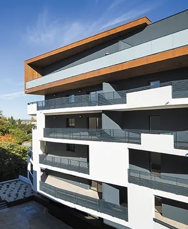 Façade principale du bâtiment haut avec ses grandes loggias orientées sud- ouest dont les rives en béton peint en blanc soulignent le déploiement.