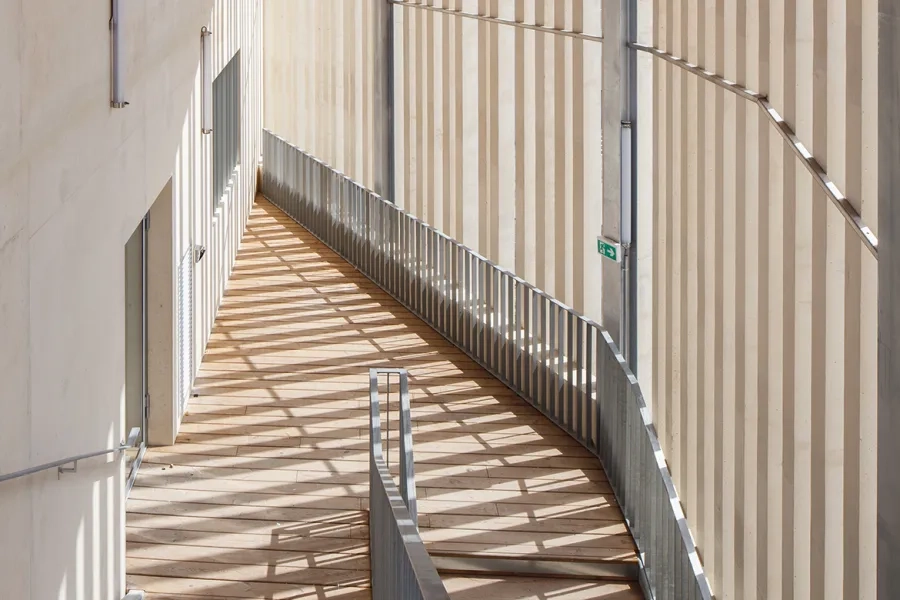 Les lames béton des claustras, réalisées en préfabrication foraine, permettent de créer une enveloppe continue qui intègre les espaces de circulation à la volumétrie générale. Les lames béton des claustras, réalisées en préfabrication foraine, permettent de créer une enveloppe continue qui intègre les espaces de circulation à la volumétrie générale.