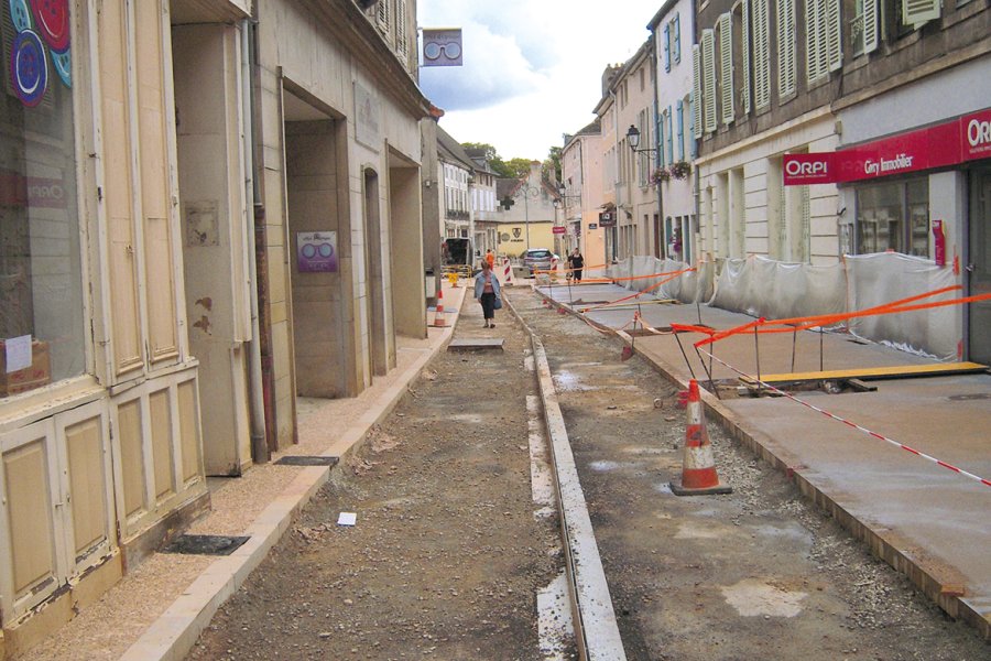 Rue de la République. Mise en œuvre manuelle du béton sur les trottoirs. Tiré à la règle sans vibration, le béton doit présenter une consistance 