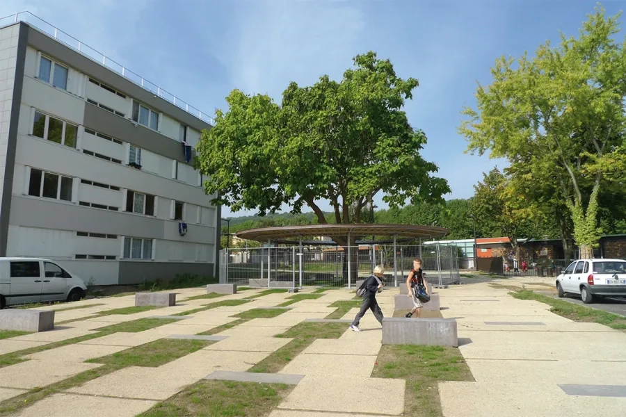 Des banquettes en béton chocolat ponctuent cet espace réalisé avec des dalles en béton coulées en place, ton pierre avec carbure de silicium désactivé, et des joints en gazon