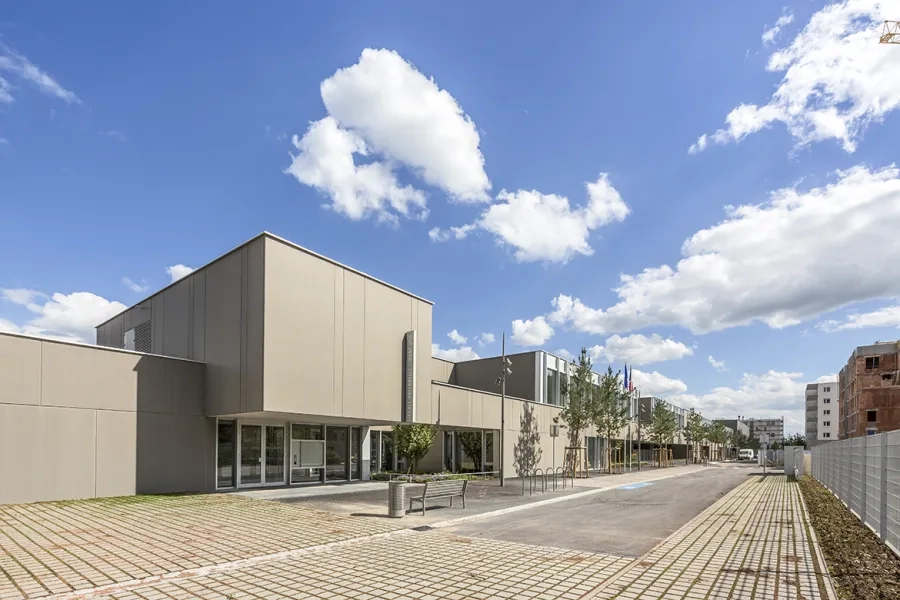 Le groupe scolaire et le gymnase s’inscrivent dans un bâtiment dont l’enveloppe dessine un écrin fédérateur et qualifie l’espace public de la promenade. Le groupe scolaire et le gymnase s’inscrivent dans un bâtiment dont l’enveloppe dessine un écrin fédérateur et qualifie l’espace public de la promenade.