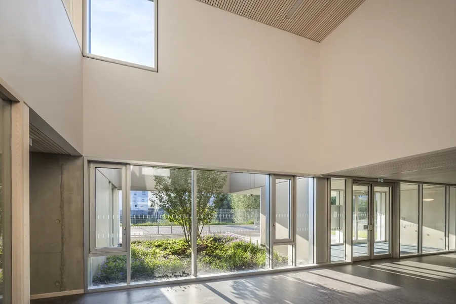 Dans le hall d’entrée de l’école maternelle, une fenêtre intérieure, à l’étage, crée un lien visuel avec l’école élémentaire. Dans le hall d’entrée de l’école maternelle, une fenêtre intérieure, à l’étage, crée un lien visuel avec l’école élémentaire.