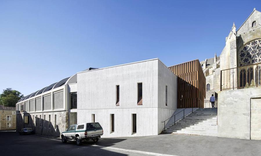 Depuis la rue basse, le nouveau volume en béton blanc brut qui abrite les bureaux de la médiathèque.