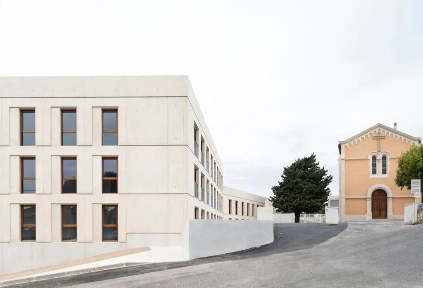 Calée dans la topographie du site, la nouvelle opération s’insère harmonieusement dans l’existant et transforme l’ancien parvis de l’église en une véritable place publique.