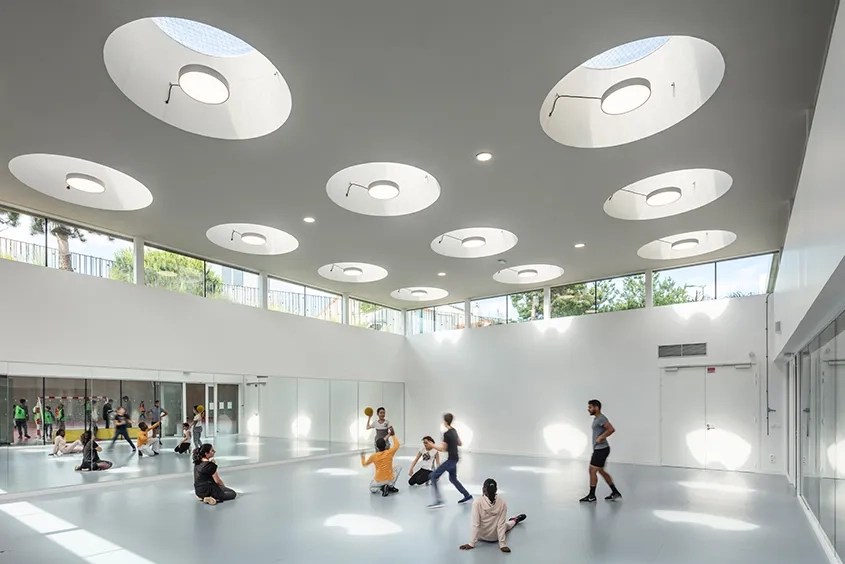 Vue sur la salle de gymnastique caractérisée par son ambiance blanche et lumineuse.