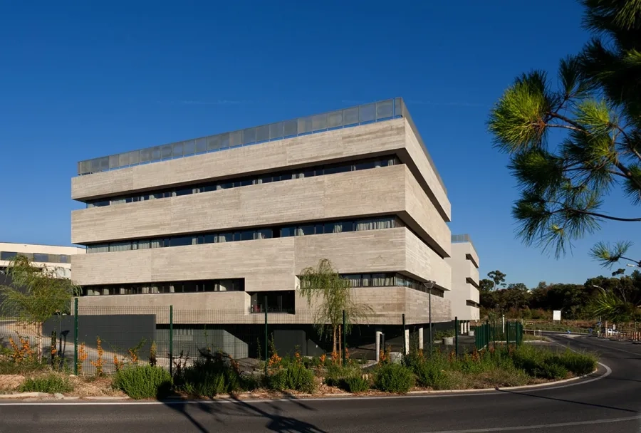 angle ouest. Le bâtiment est soulevé, laissant  filer le sol naturel et dégageant des places de stationnement.