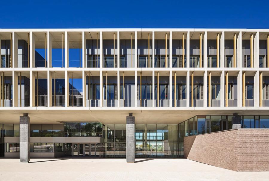 entrée en façade est, tout en transparence. Par leur disposition en retrait du plancher, les poteaux triangulaires en béton noir accentuent l’e et de soulèvement des étages.