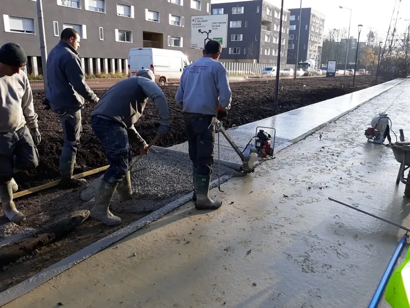 Le tirage du béton au rouleau Striker. Il n’a pas été vibré pour ne pas faire descendre le granulat, qui doit rester en surface pour le bon aspect visuel de la finition piqué.