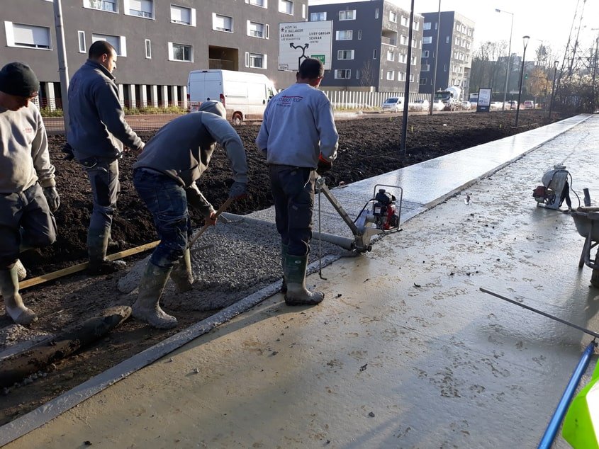 Le tirage du béton au rouleau Striker. Il n’a pas été vibré pour ne pas faire descendre le granulat, qui doit rester en surface pour le bon aspect visuel de la finition piqué.